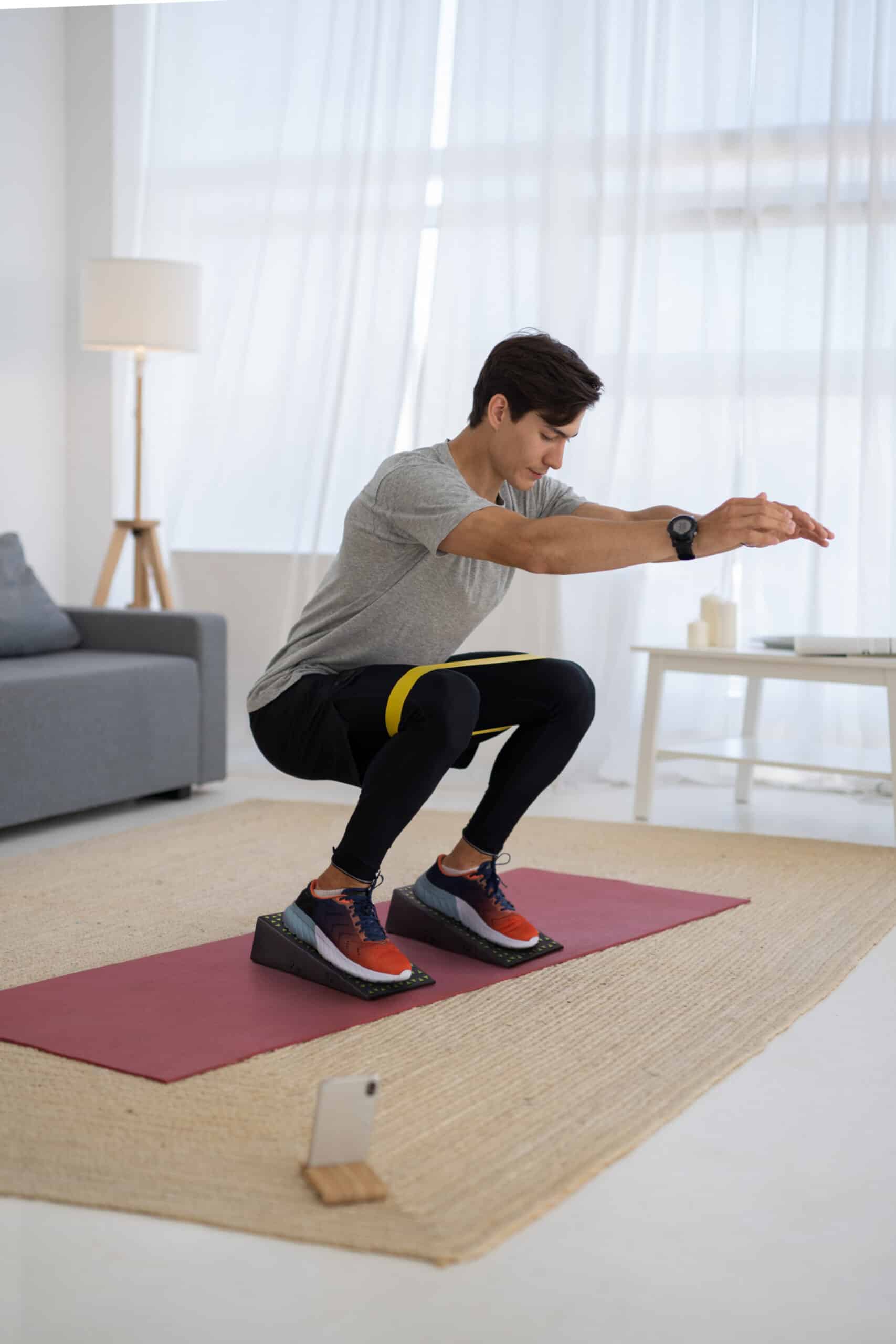 Man performing deep squats with squat wedges at home for improved form