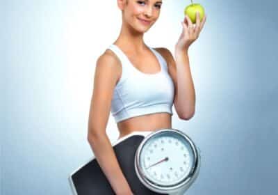 Woman holding a scale and apple as part of healthy lifestyle tips