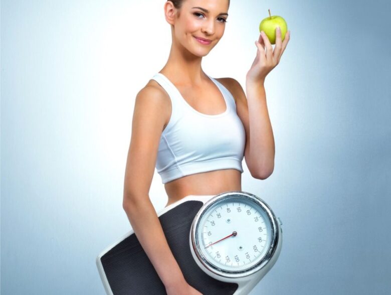 Woman holding a scale and apple as part of healthy lifestyle tips