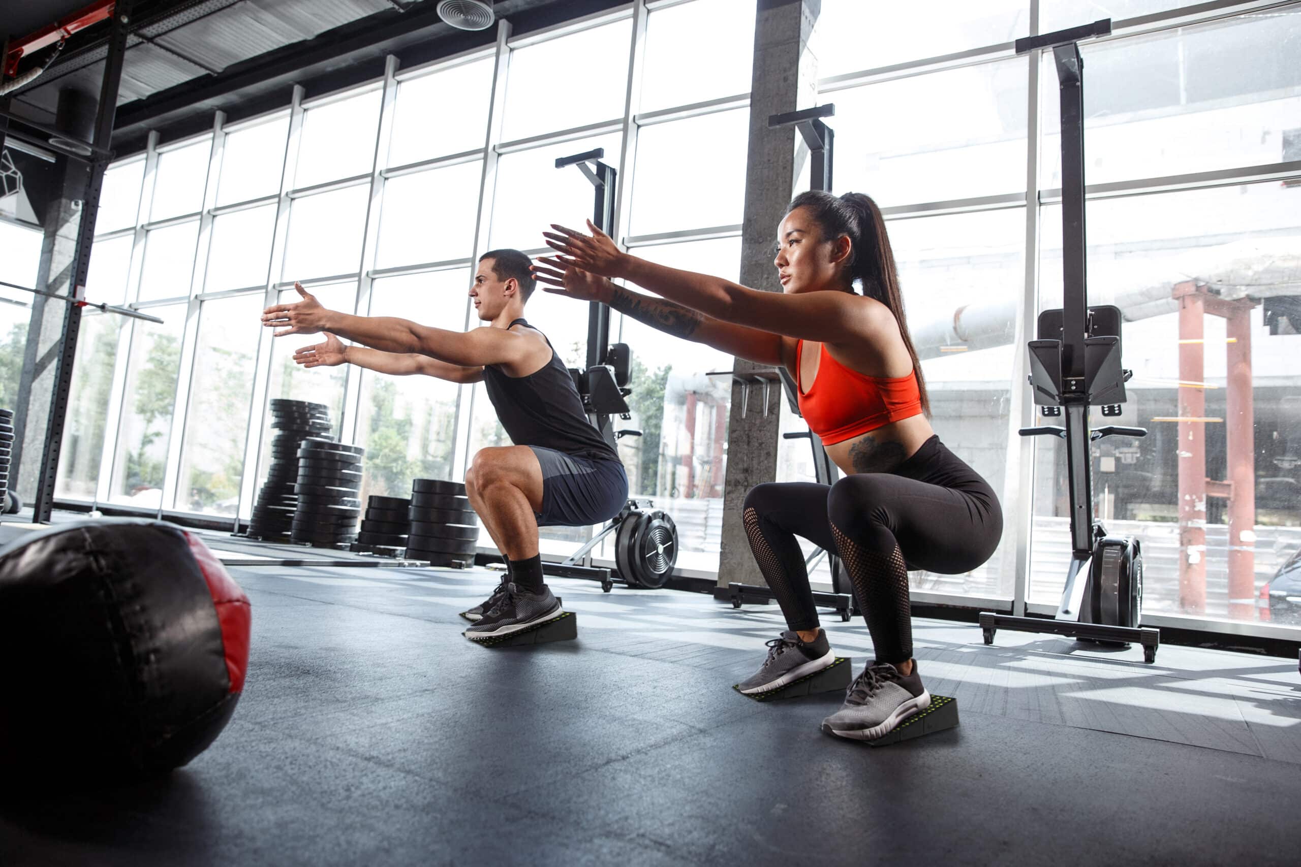 Two people performing versatile workout routines with Flexelent wedges in the gym