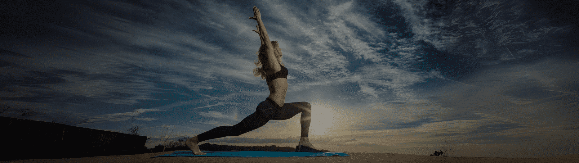 Woman performing yoga stretch using Flexelent squat wedges outdoors at sunrise.